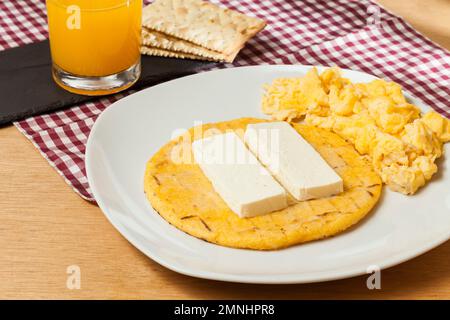 Gustosa colazione tradizionale in Colombia; l'arepa di mais giallo con formaggio e uova strapazzate. Foto Stock