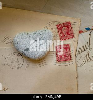 Vecchie buste con francobolli e pietra a forma di cuore Foto Stock