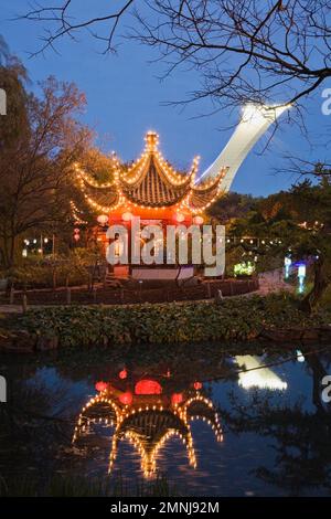 Il padiglione della piacevolezza infinita illuminato e riflesso nel laghetto del Loto durante la mostra annuale Magic of Lanterns nel Giardino Cinese al crepuscolo. Foto Stock
