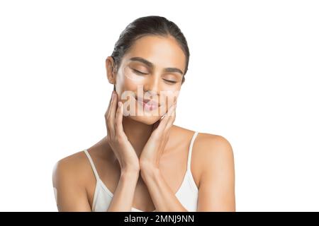 Ritratto di giovane donna sorridente che applica la crema per il viso Foto Stock