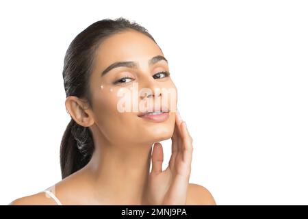 Ritratto di giovane donna sorridente che applica la crema per il viso Foto Stock