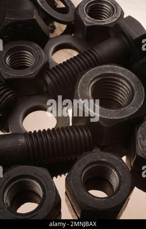Bulloni, dadi e rondelle grandi in acciaio nero su fondo di stagno. Foto Stock
