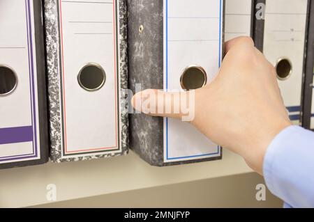 Mano di un uomo d'affari che passa attraverso le lime sugli scaffali in un ufficio Foto Stock