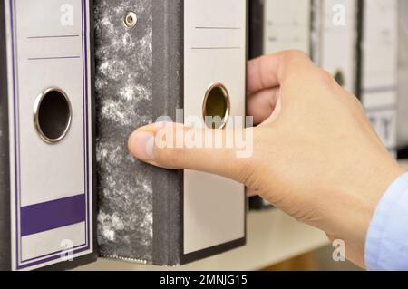 Mano di un uomo d'affari che passa attraverso le lime sugli scaffali in un ufficio Foto Stock