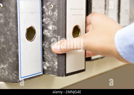 Mano di un uomo d'affari che passa attraverso le lime sugli scaffali in un ufficio Foto Stock