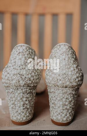 Un semplice anello di aggancio tra un paio di scarpe da sposa coperte di perle Foto Stock