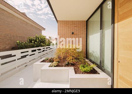 Ingresso di una casa con corridoio con finestra di design e piantatrice in muratura rivestita in marmo bianco Foto Stock