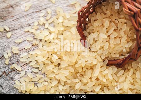 giallo riso marrone, usato per risotto su un tagliere di legno Foto Stock