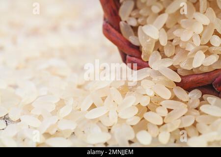 giallo riso marrone, usato per risotto su un tagliere di legno Foto Stock