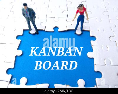 Persone in miniatura con la parola KANBAN BORDO su uno sfondo blu bianco puzzle. Foto Stock