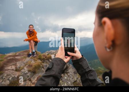 Due amici giovane donna amici escursionisti contro le montagne scattare una foto di un iphone in natura, Selfie smartphone moderno, utilizzando Telefono, amicizia Foto Stock
