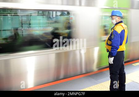 Lavoratore della sicurezza ferroviaria in piedi sulla piattaforma della linea JR Yamanote a Shibuya, Tokyo, Giappone. Foto Stock