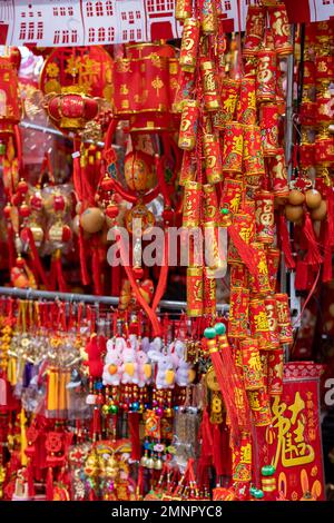 Una bancarella a bordo strada che vende le decorazioni di Capodanno in rosso e giallo oro Foto Stock