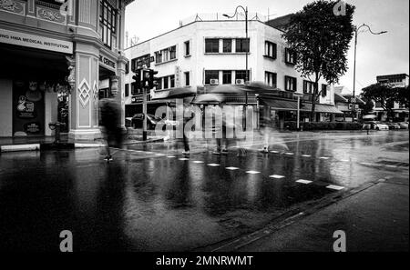 I pedoni camminano sotto i loro ombrelloni a Katong, Singapore Foto Stock