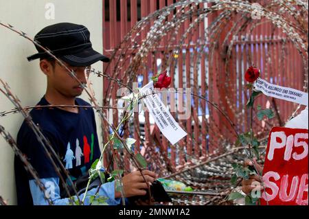A protester places red roses with messages on a barbed wire barricade leading to the Presidential Palace during a rally to mark the 32nd anniversary of the 'People Power' revolution Sunday, Feb. 25, 2018 in Manila, Philippines. The protesters scored President Rodrigo Duterte, who skipped the ceremony for the second straight year Sunday, for his 'creeping dictatorship' and are demanding for his ouster. (AP Photo/Bullit Marquez)