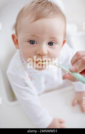 Questo ha un buon gusto. Vista ad angolo alto di un bambino che viene nutrito da sua madre. Foto Stock