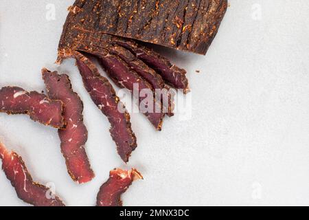 Biltong sudafricano tagliato di recente su sfondo chiaro con messa a fuoco selettiva e spazio copia Foto Stock