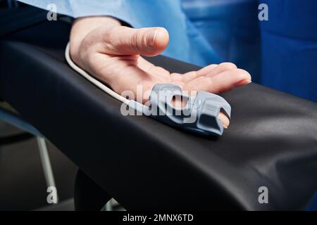 Pulsossimetro sul dito del paziente per il rilevamento della saturazione di ossigeno durante il funzionamento in ospedale. Pulsossimetria Foto Stock