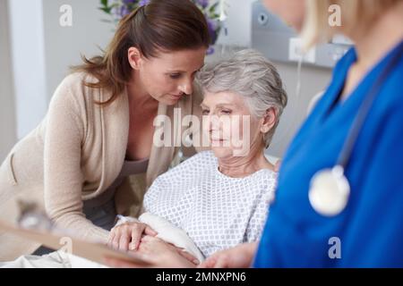 Ho appena sentito la notizia... Una figlia che consolava sua madre in ospedale dopo aver parlato con l'infermiera. Foto Stock