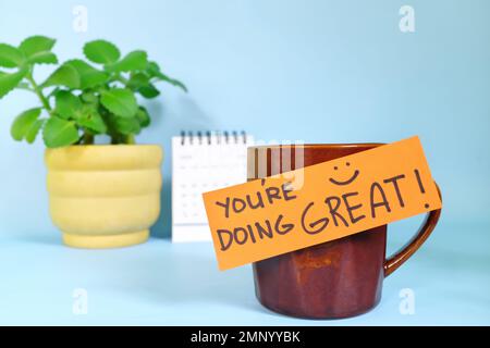 State facendo le grandi parole di concetto di incoraggiamento. Messa a fuoco selettiva di una tazza di caffè con messaggio scritto a mano su carta lucida. Foto Stock