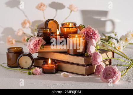 Un set di candele aromatiche diverse in vasetti di vetro marrone. Candela profumata fatta a mano. Le candele di soia stanno bruciando in un vaso. Aromaterapia e relax in spa e casa. Fuoco in vaso marrone. Foto Stock