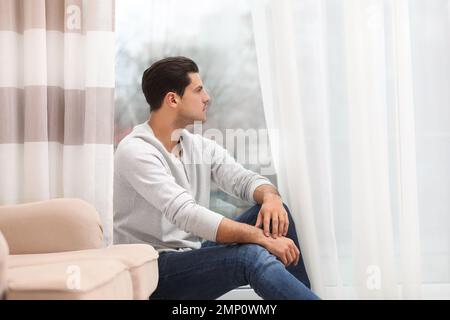 Bell'uomo che riposa vicino alla finestra di casa Foto Stock