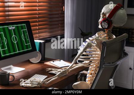 Scheletro umano con cuffie che giocano al coperto Foto Stock