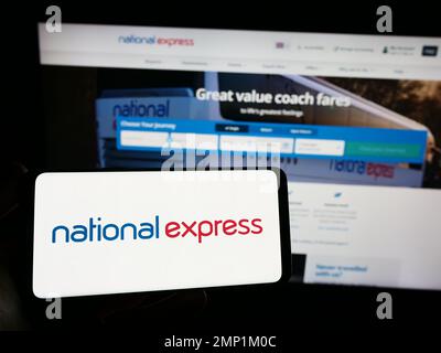 Persona che tiene uno smartphone con il logo della società britannica National Express Group plc (NX) sullo schermo di fronte al sito Web. Messa a fuoco sul display del telefono. Foto Stock