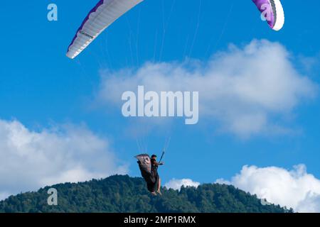 Batumi, Georgia - 28 2022 luglio: L'uomo vola su un parapendio e sventola la mano sullo sfondo di un cielo blu brillante Foto Stock