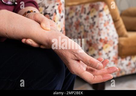 Immagine ravvicinata del polso da massaggio della donna anziana. Soffrire di spasmo della mano. Donna anziana con dolore o sforzo muscolare. Concetto di problema di salute dell'anziano. Foto Stock