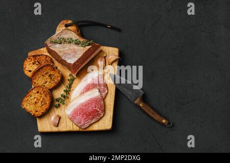 Vista dall'alto della carne di maiale salata con lardo sul tagliere in legno Foto Stock