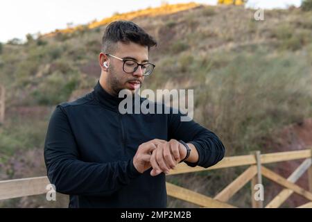 Ragazzo atletico che controlla la frequenza cardiaca sul suo orologio intelligente. Foto Stock