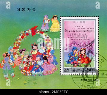 Francobollo nordcoreano del 2000 con canzoni per bambini e bambini in abiti tradizionali Hanbok. Foto Stock