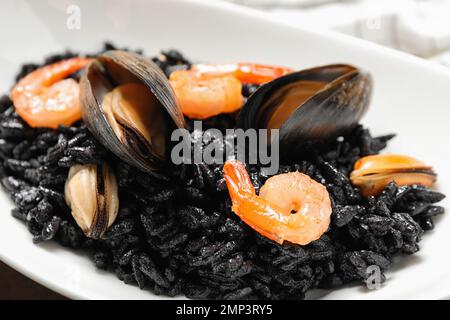 Delizioso risotto nero con frutti di mare in piatto, primo piano Foto Stock