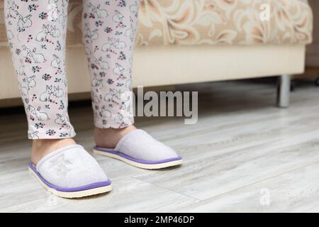 l'uomo mette le ciabatte sul letto. uomo che esce dal letto la mattina. uomo dopo svegliarsi seduto sul letto. Donna in pigiama. l'uomo si sveglia Foto Stock