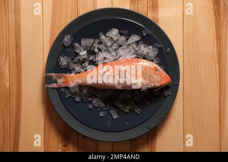 Pesce fresco crudo con ghiaccio su tavolo di legno, vista dall'alto Foto Stock