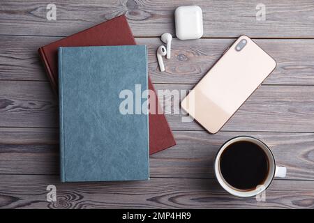 Libri, caffè, auricolari e telefono cellulare su tavolo di legno grigio chiaro, piatto Foto Stock