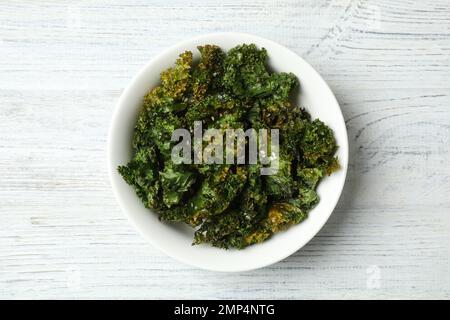 Gustose patatine di kale al forno su un tavolo di legno bianco, vista dall'alto Foto Stock