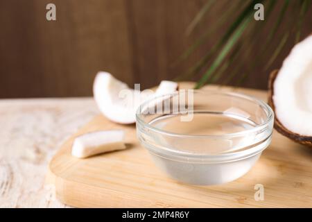 Olio di cocco in ciotola di vetro su tavola di legno, primo piano Foto Stock