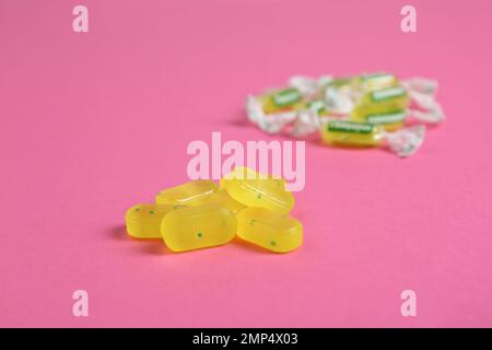 Mucchio di gustose gocce di limone su sfondo rosa Foto Stock