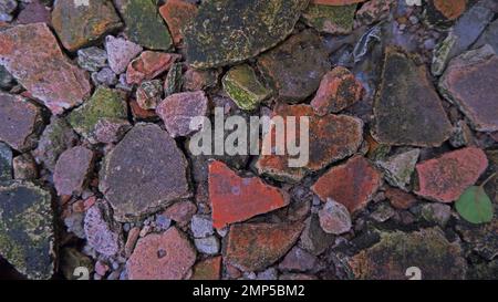 Vista ravvicinata di frammenti e frammenti di piastrelle sul tetto, che formano Una disposizione simile a un Puzzle sul terreno Foto Stock