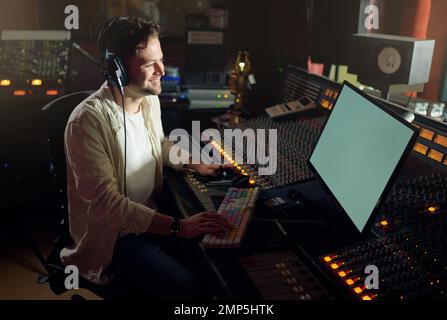 Cuffie per produttori, sorridenti o per computer in registrazione musicale, mixaggio audio o composizione di brani in studio. Musicista, DJ o uomo felice sulla tecnologia e. Foto Stock