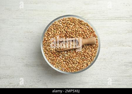 Grano saraceno verde crudo in ciotola su tavolo di legno bianco, vista dall'alto Foto Stock