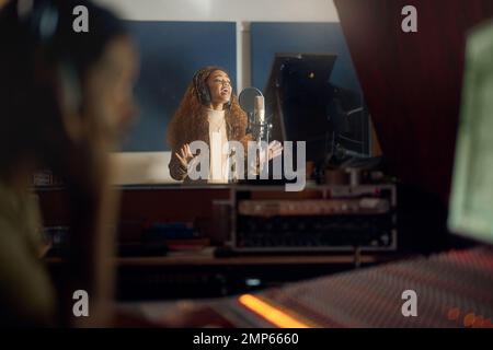 Musicista, canto o microfono da studio in album, audio o radio cover durante la produzione notturna. Cantante, artista o donna in serata canzone Foto Stock