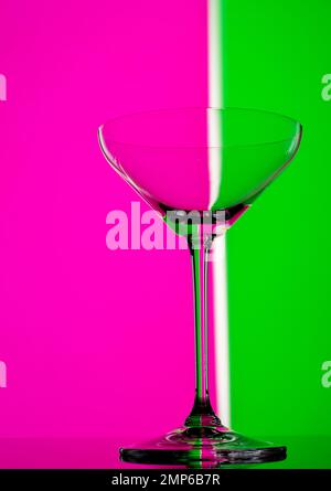 Cocktail party in vetro in colori al neon. Primo piano su sfondo colorato. Bicchiere di champagne moderno ed elegante. Foto Stock