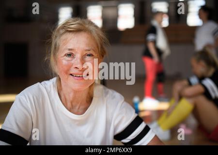 Donna anziana felice prima della partita di basket in palestra. Foto Stock