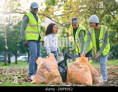 Bambino con gruppo di volontari per la pulizia del parco con sacco per rifiuti per un ambiente pulito. Uomini, donne e bambini aiutano e imparano a favore dell'ambiente Foto Stock