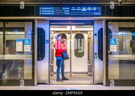 Una donna si trova su una linea Elizabeth Line della metropolitana di Londra alla stazione di Paddington in attesa della sua partenza. Le porte del treno e le barriere di sicurezza sono aperte. Foto Stock