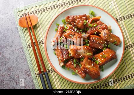 Costolette di guglia al barbecue dolci e aspre con cipolla verde e primo piano di sesamo in un piatto sul tavolo. Vista orizzontale dall'alto Foto Stock