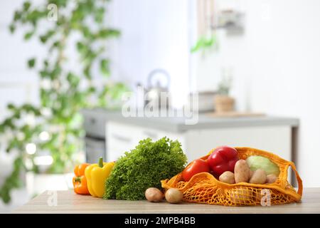 Sacchetti di rete con verdure su tavolo di legno in cucina Foto Stock